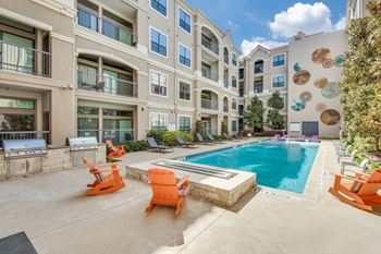 A swimming pool surrounded by orange chairs in front of a building.